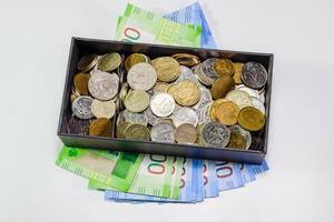 monedas de diferente denominaciones en un cerdito banco caja. papel rublos debajo el cerdito banco. nuevo billetes de Rusia foto