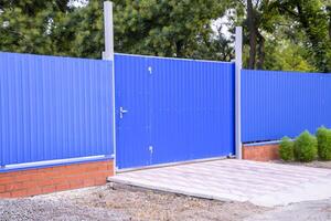 Fence and gate from sheets of blue corrugated metal. photo