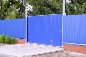 Fence and gate from sheets of blue corrugated metal. photo