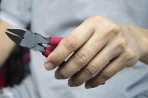 Mechanic holds red handle cutting pliers, mechanic's tools photo