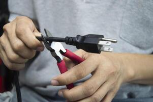 Technician uses red-handled pliers to cut wires, mechanic's tools photo