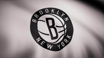 basquetebol Brooklyn redes bandeira é acenando em transparente fundo. fechar-se do acenando bandeira com Brooklyn redes basquetebol clube logotipo, desatado laço. editorial animação video