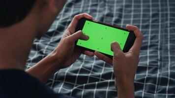 top view Human hand holding smartphone green screen with gaming gestures on blue background photo