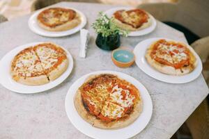 Pizza Margherita cut into four pieces lies on plates on the table photo