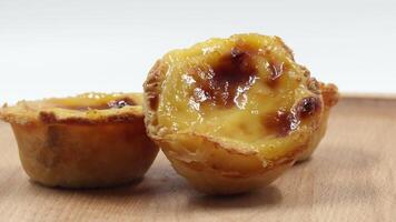 Three traditional Portuguese desserts Pastel de Nata or Pastel de Belem. Egg custard tart sprinkled with cinnamon. Rotating popular Portuguese pie with golden brown crust on a wooden background. video