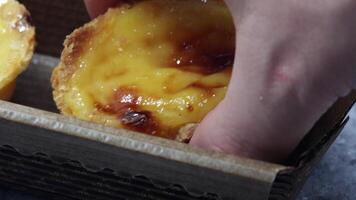 A baker's or cook's hand places a fresh and hot crispy puff pastry pie with egg custard into a paper package in a cafe. Traditional Portuguese dessert Pastel de Nata or Pastel de Belem. video
