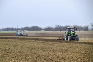 lozano y aflojar el suelo en el campo antes de siembra. el tractor arados un campo con un arado foto