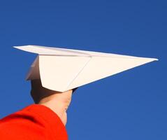 White paper airplane in hand against the sky. A symbol of freedom on the Internet photo