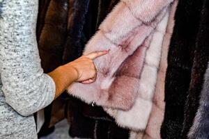 el niña toques el piel en el piel abrigo. elegir un piel Saco en el Tienda foto