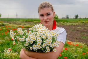 joven niña con un ramo de flores de margaritas en campo. margaritas en un amapola campo. foto