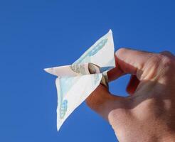 Denominations of Russian money, folded in the airplane against the blue sky in hand photo