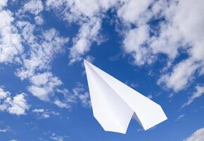 White paper airplane in a blue sky with clouds. The message symbol in the messenger photo