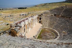 Ancient antique amphitheater in city of Hierapolis in Turkey. Steps and antique statues with columns in the amphitheater photo