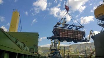 Industrial seaport. The rotation of the car with grain using a tower crane photo