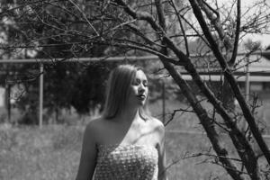 negro y blanco foto, niña en el jardín en un prado en un vestido. foto