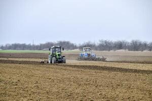 Lush and loosen the soil on the field before sowing. The tractor plows a field with a plow photo