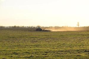 tractor a puesta de sol arado arado un campo. labranza el suelo en el otoño después cosecha. el final de el temporada foto