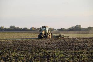 Tractor plowing plow the field. Tilling the soil in the fall after harvest. The end of the season photo
