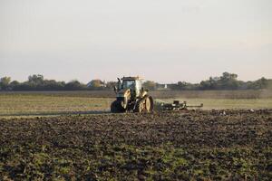 tractor arada arado el campo. labranza el suelo en el otoño después cosecha. el final de el temporada foto