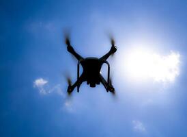 Drone DJI Phantom 4 in flight. Quadrocopter against the blue sky with white clouds. The flight of the copter in the sky. photo