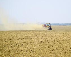 Tractor rides on the field and makes the fertilizer into the soi photo