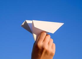 blanco papel avión en mano en contra el cielo. un símbolo de libertad en el Internet foto