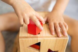 linda caucásico pequeño niña jugando en el piso a hogar con eco de madera juguetes montessori juguete. el niño jugando educativo juegos. foto