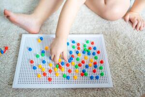 bonito pequeño niña jugando con seta uña mosaico a hogar. pasatiempo y ocio hora foto