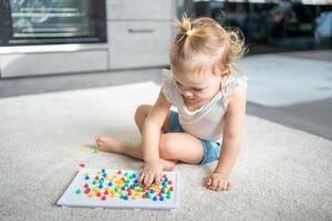 bonito pequeño niña jugando con seta uña mosaico a hogar. pasatiempo y ocio hora foto