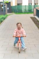 pequeño niña montando equilibrar bicicleta en el patio de el residencia en praga, Europa foto