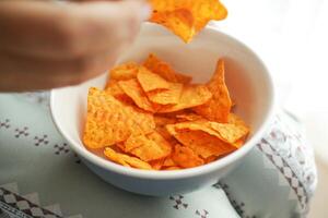 mujer mano recoger patata papas fritas desde un cuenco foto