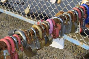 Love locks hung by newlyweds and lovers on the fence near the river. A symbol of strong relationships and eternal love photo