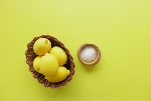 Coarse salt in a bowl and lemon on yellow background photo