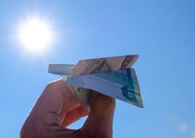 Denominations of Russian money, folded in the airplane against the blue sky in hand photo