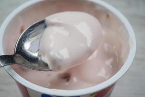 spoon picks fresh yogurt in a plastic container photo