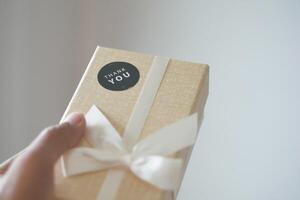 hand holding a gift box with a thank you sticker photo