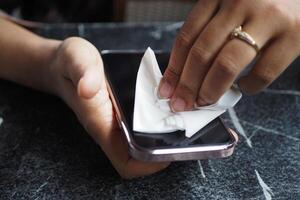 women cleaning mobile phone display with tissue photo