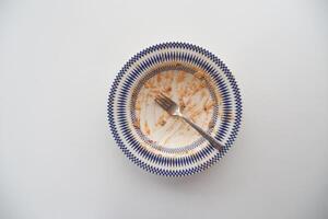 An empty dirty plate with a fork. photo