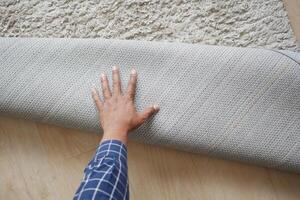 men hand rolling out new rug. photo