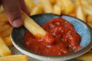 toma detallada de papas fritas bebiendo salsa en la mesa foto