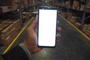 business owner holding phone mock up in warehouse. photo