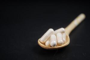 closeup of herbal medicine capsule on a wooden spoon photo