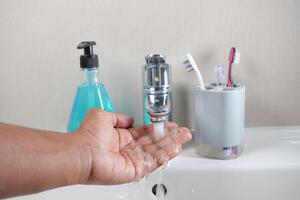 young man washing hands with soap warm water photo