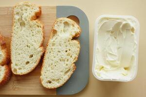 Mantequilla fresca en un recipiente con pan sobre fondo blanco. foto