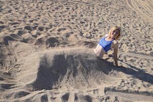 niña en un bikini en el playa enterrado en medio en el arena. foto