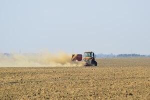 Tractor rides on the field and makes the fertilizer into the soil. Fertilizers after plowing the field. photo