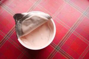 fresh yogurt in a plastic container and spoon on table photo