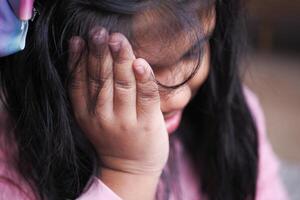 a upset child girl cover her face with hand photo