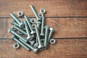 metal screw or bolt and nuts wooden background. photo