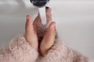 child washing hands with warm water photo
